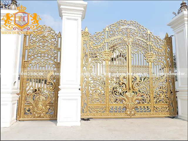 Mẫu cổng nhà đẹp được thiết kế từ chất liệu hợp kim nhôm đúc là 1 ý tưởng vô cùng tuyệt vời cho không gian. Màu vàng đồng sang trọng kết hợp với các họa tiết mềm mại, tinh tế thích hợp với nhiều không gian khác nhau.